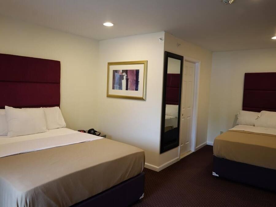 A hotel room with two beds, a large mirror, and a framed picture on the wall.