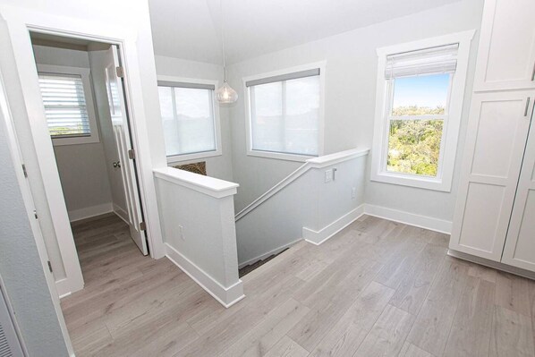Habitación con escalera, paredes blancas y vistas a zonas verdes.