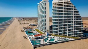 Un hôtel situé en bord de mer, compos é de plusieurs immeubles de grande hauteur, avec une piscine et une plage.