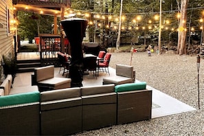 Relax in a serene outdoor space with wicker furniture, cushioned seating, and string lights.