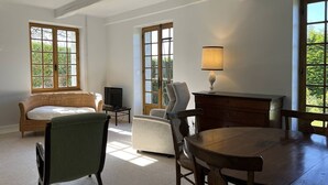Een kamer met een bed, een televisie, een bureau met lamp, een stoel en een tafel.