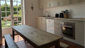 Een keuken met een houten tafel, witte kastjes, een vaatwasser en een oven.