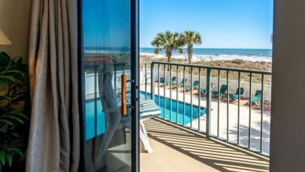 Un balcón con vista a la playa y a la piscina.