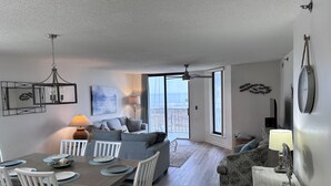Una sala de estar moderna con comedor, sofá y vistas al exterior.