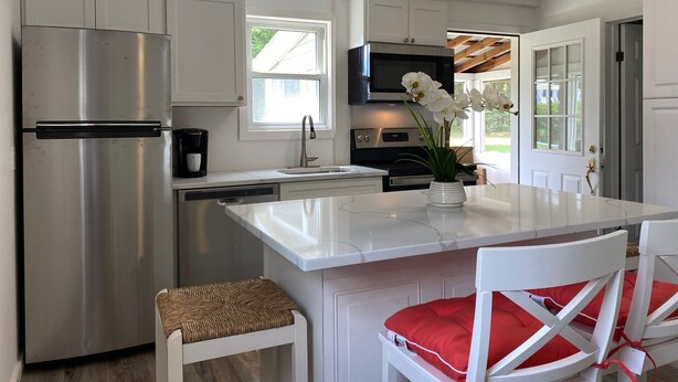 Una cocina moderna con armarios blancos, electrodomésticos de acero inoxidable y una isla central con un florero.