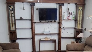 Ein Wohnzimmer mit zwei Sofas, einem Fernseher, Holzböden und einem gemusterten Teppich.