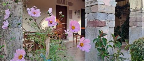 A courtyard with stone arches, a wooden table, and potted plants.