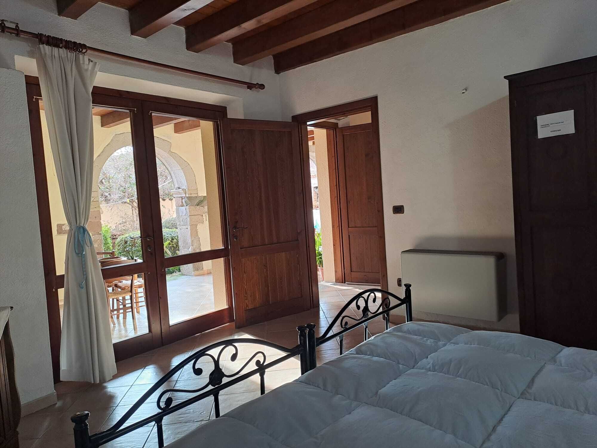 Un dormitorio con cama, una puerta de madera y vista a un espacio exterior.