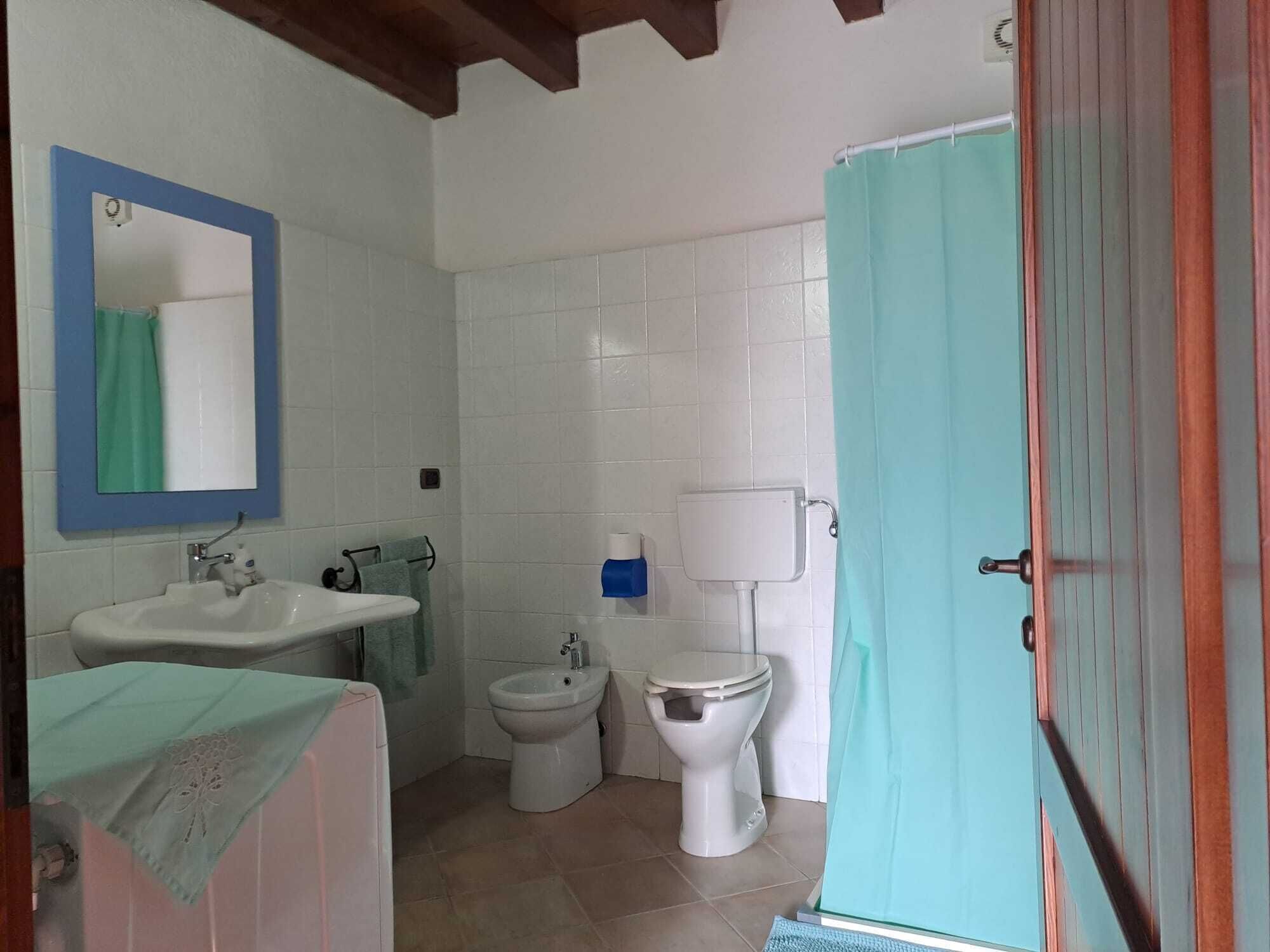 A bathroom with a sink, bidet, toilet, and a mirror with a blue frame.