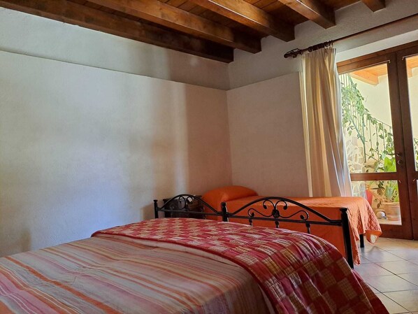 Un dormitorio con cama, ventana con cortinas y vista a zonas verdes.