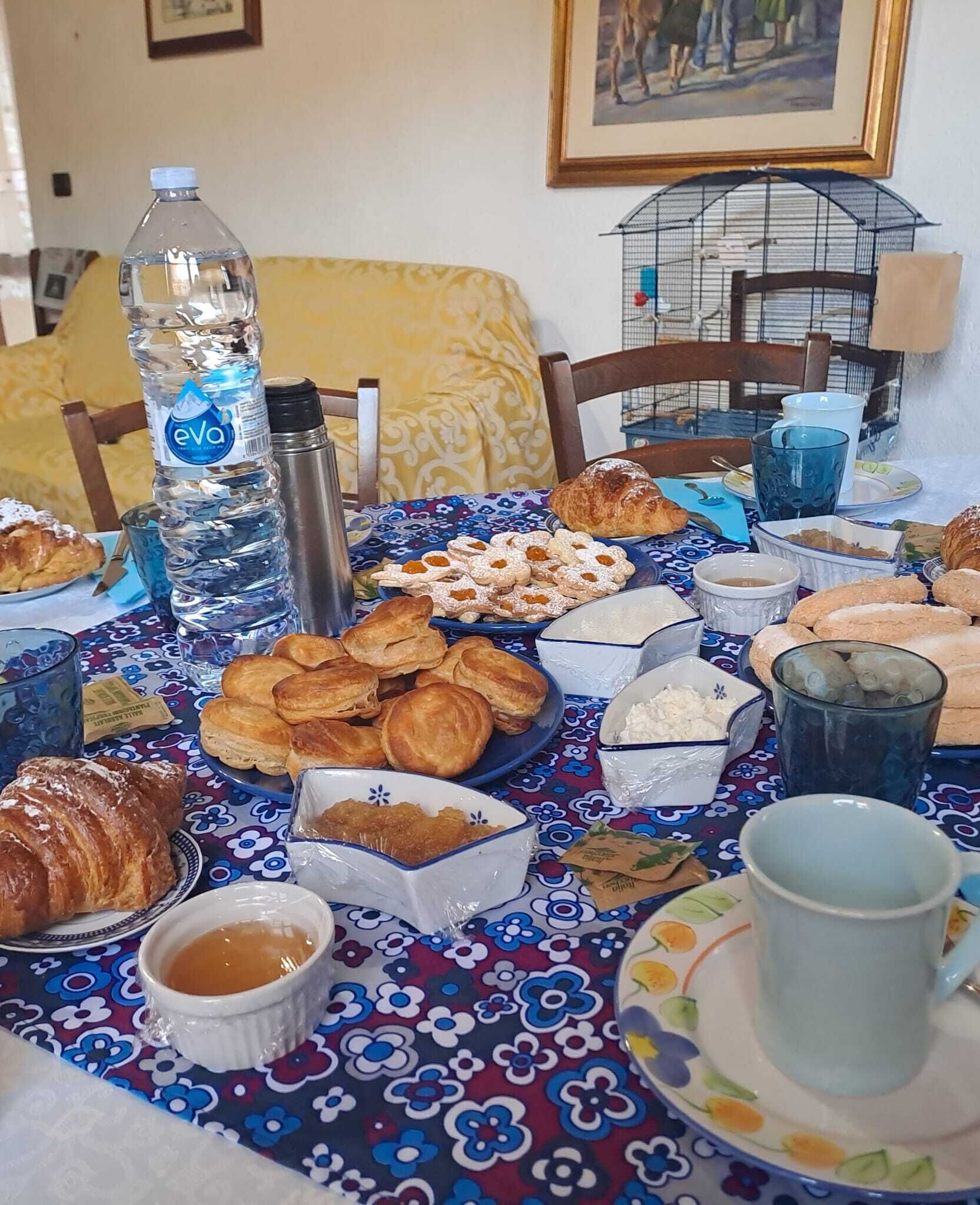 A breakfast table with pastries, a water bottle, and a thermos.