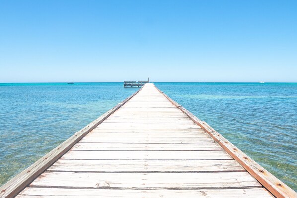 A wooden pier extending into a clear blue sea. - Beach homes for families or larger groups!- Casa Coral and Palmera (Roatan)