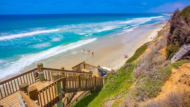 A beach with a wooden staircase leading down to the shore, a sandy beach, and the ocean. - Ocean+Sunset Views * 3 Levels * 5 Outdoor Areas (Encinitas)