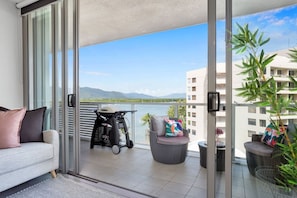 Enjoy the serene view of the water and distant mountains from this balcony, featuring a comfortable sofa and outdoor seating area.