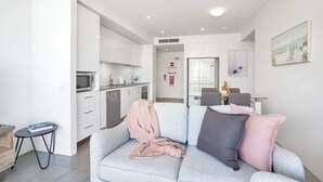 A modern living room with a grey sofa, a small table, and a kitchen area in the background.