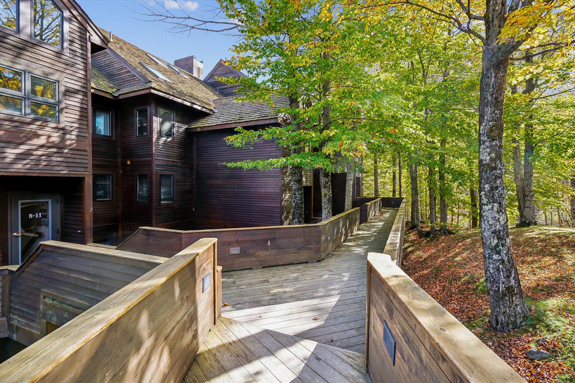 A wooden building with a deck and a forested area.