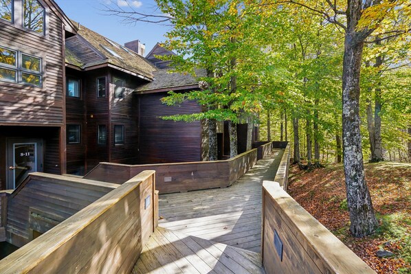 A wooden building with a deck and a forested area.
