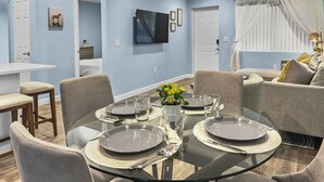 Un comedor moderno con una mesa de vidrio dispuesta para cuatro personas, rodeada de asientos cómodos.