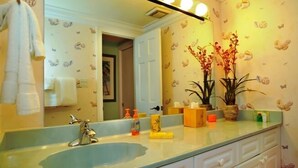 Un baño con lavamanos, espejo y plantas decorativas.