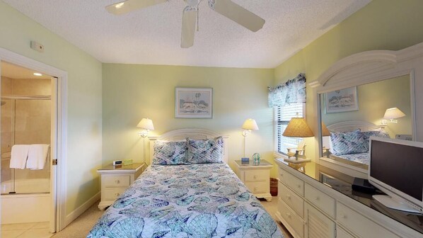 Un dormitorio con cama, mesitas de noche, cómoda, televisor y ventilador de techo.