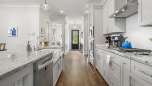 A modern kitchen with white cabinets, a marble countertop, and stainless steel appliances.