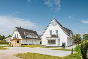 Une maison moderne à deux étages, dotée d’un grand balcon et d’un garage.