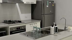 A modern kitchen with white cabinets, stainless steel appliances, and a grey countertop. - Modern House in Newton (Newton)