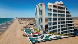 Een hotel aan het strand met meerdere verdiepingen, een zwembad en een strandgedeelte.