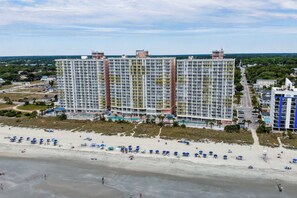 A beachfront hotel with multiple high-rise buildings, a sandy beach with umbrellas, and a clear view of the ocean. - Spacious Oceanfront Condo - Bay Watch 1138 (North Myrtle Beach)