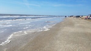 A beach with a sandy shore and ocean waves. - 10 minutes walk to the beach .Covered rv spot on concrete slab. NEW CAMPER (Bolivar Peninsula)