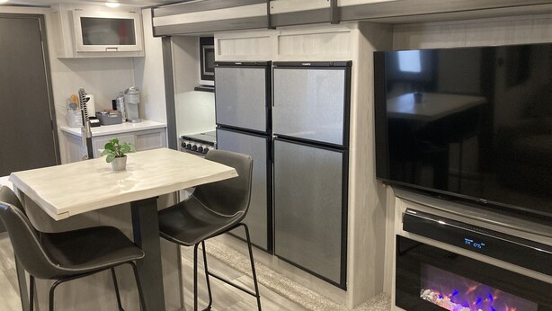 A modern kitchen with a dining area, stainless steel appliances, a flat-screen TV, and a built-in fireplace. - 10 minutes walk to the beach .Covered rv spot on concrete slab. NEW CAMPER (Bolivar Peninsula)