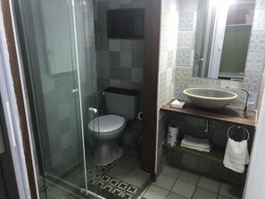 Une salle de bain avec une douche à parois de verre, des toilettes, un lavabo avec un meuble-vasque et un miroir au-dessus du lavabo.