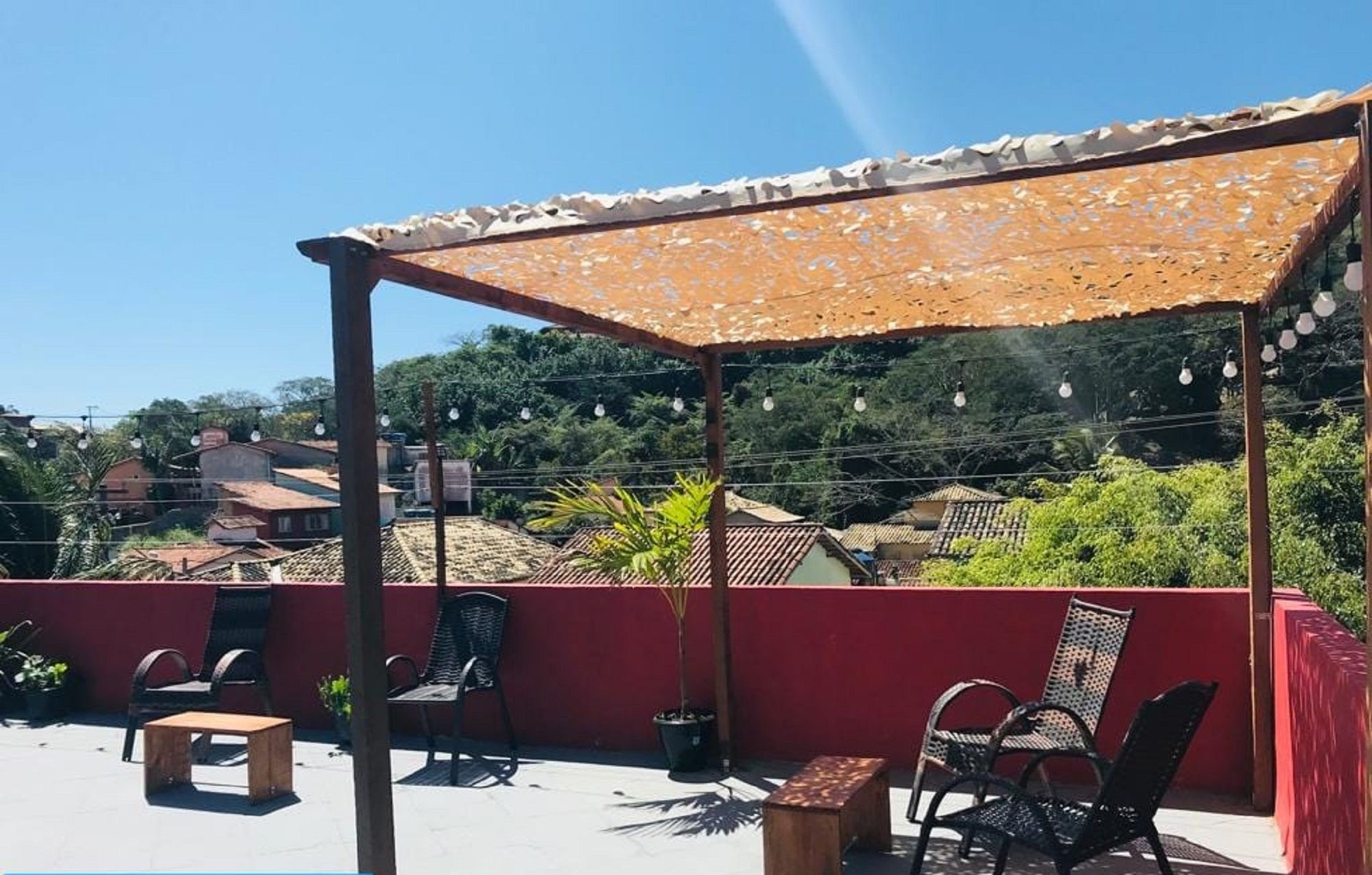 A rooftop terrace with outdoor seating, a pergola, and a view of the surrounding neighborhood.