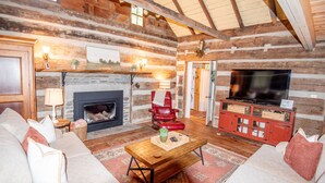Ein Holzhütten-Interieur mit Kamin, Fernseher und einem roten Ledersessel.