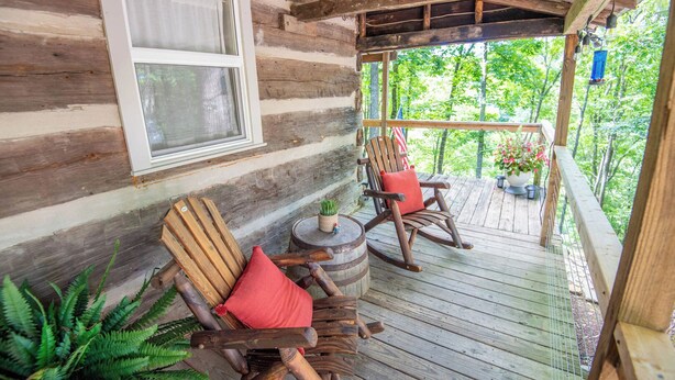 Eine Holzhütte mit Veranda, ausgestattet mit zwei Schaukelstühlen und einem kleinen Tisch.