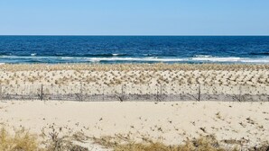 Ein Strand mit einem Zaun im Vordergrund und dem Meer im Hintergrund.