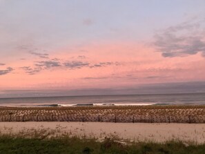 A beach with a wooden fence in the foreground and a sunset over the ocean. - Beachfront getaway on the sea (Seaside Heights)