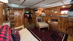 Un intérieur de chalet chaleureux avec un lit superposé, une petite kitchenette et un coin repas.