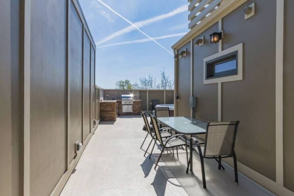An outdoor patio area with a table and chairs, a grill, and a small kitchen area.