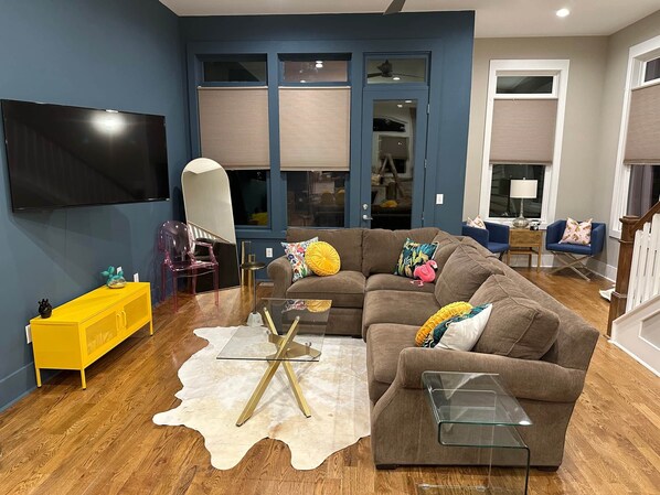 A modern living room with a sectional sofa, a glass coffee table, and a yellow sideboard.