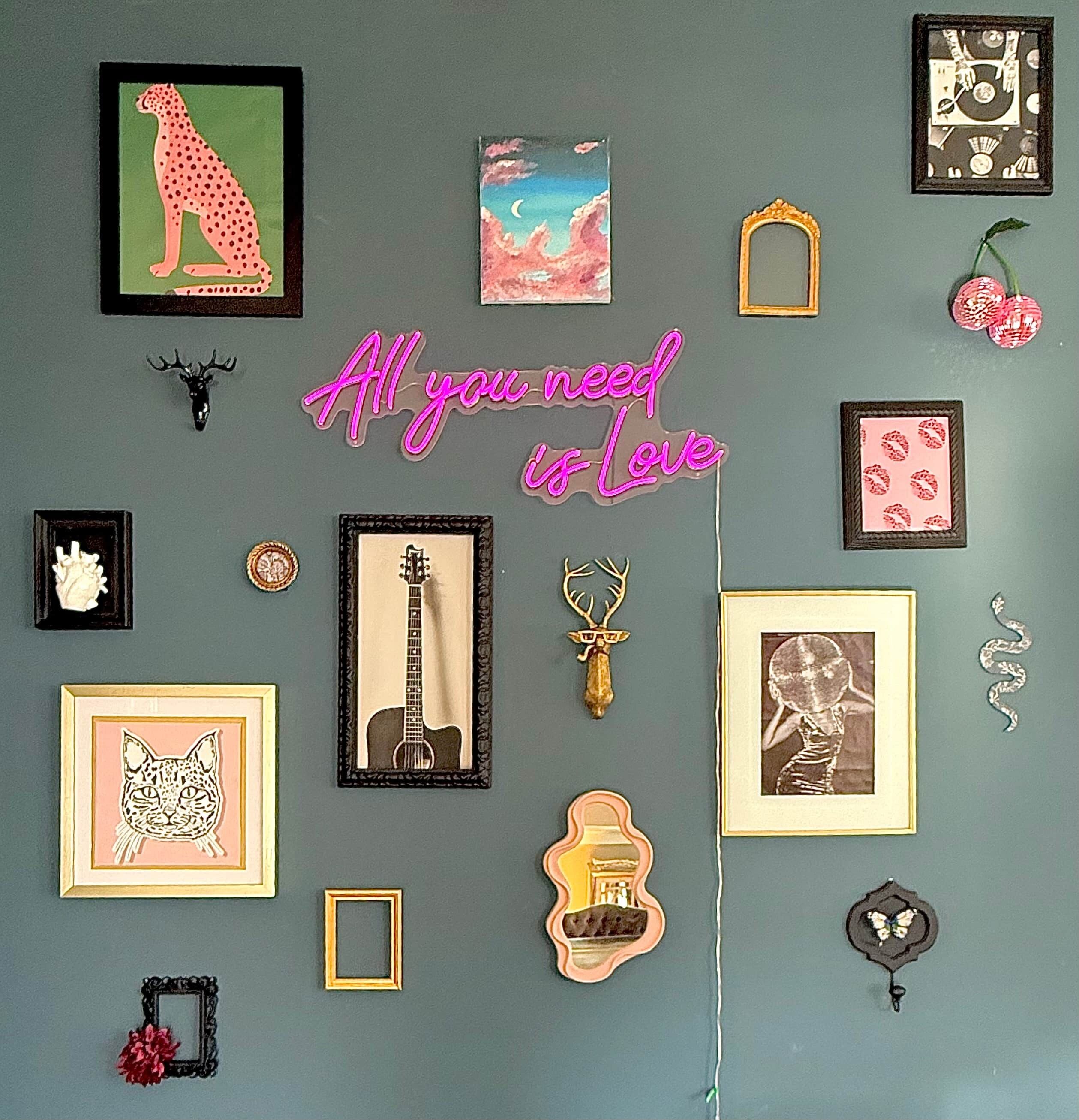 A wall with various framed artworks, including a cheetah, a guitar, and a cat.
