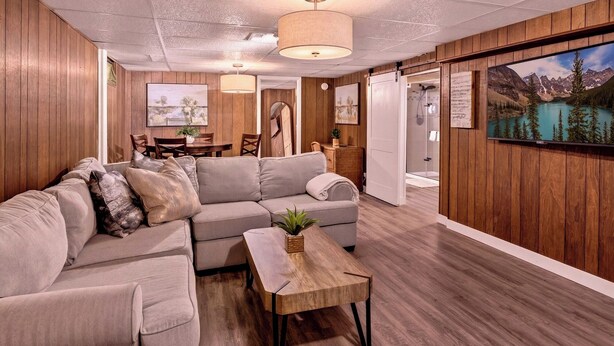 A modern living room with a sectional sofa, a wooden coffee table, and a painting of a mountain landscape. - Spacious & Cozy ~ Mins to Downtown (Springfield)