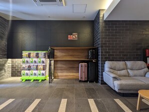 Un hall d’entrée moderne avec un espace salon, un distributeur automatique et une étagère fixée au mur.