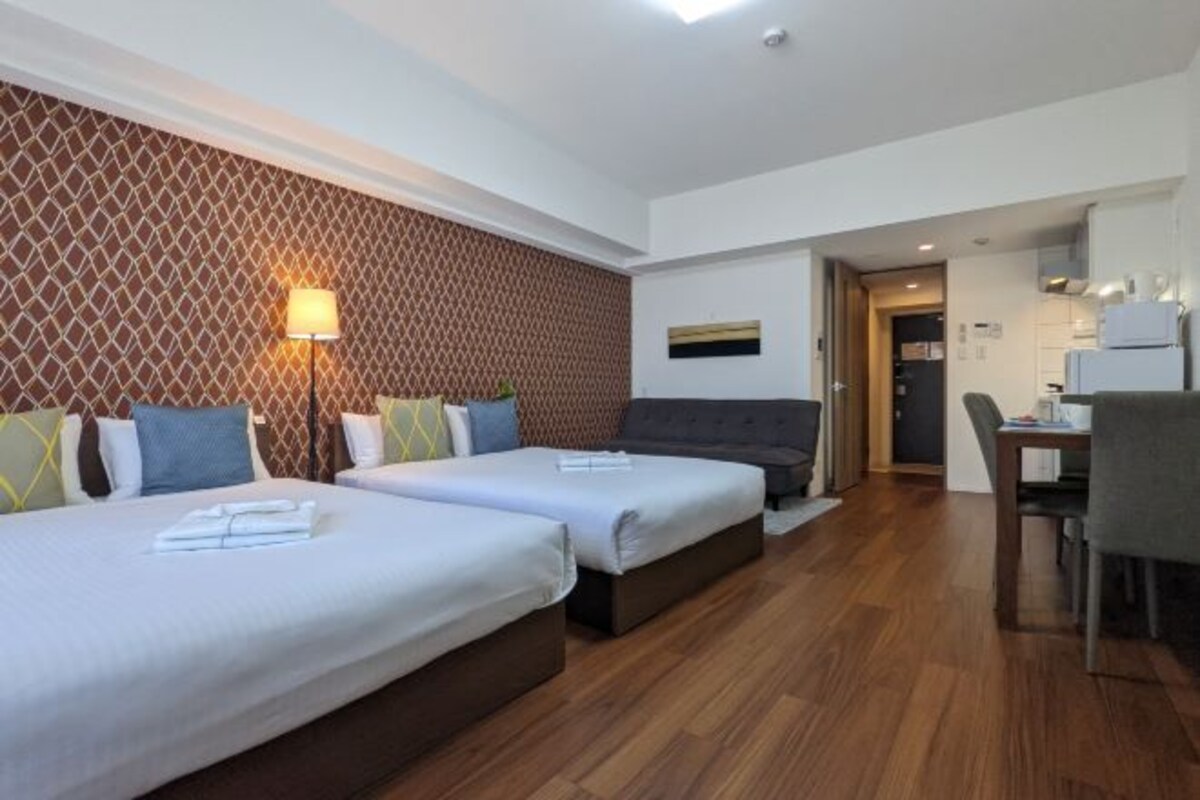 Une chambre d’hôtel avec deux lits, un bureau et une kitchenette.