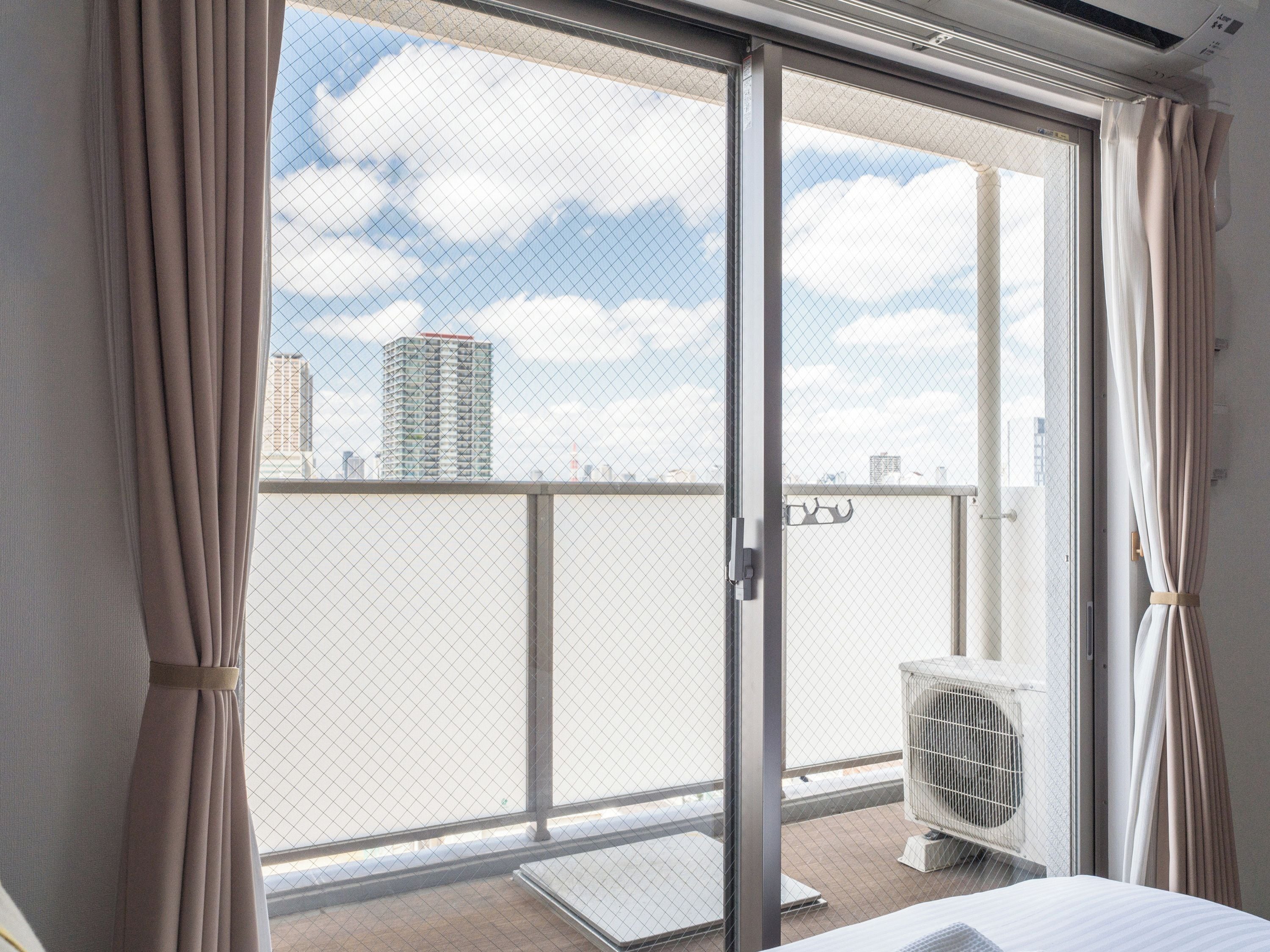 A room with a sliding glass door leading to a balcony with a city view.