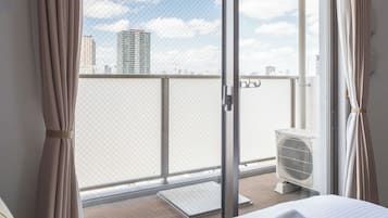A room with a sliding glass door leading to a balcony with a city view.