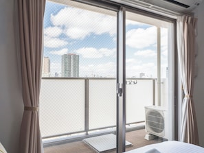 Une pièce dotée d’une porte-fenêtre coulissante donnant sur un balcon avec vue sur la ville.