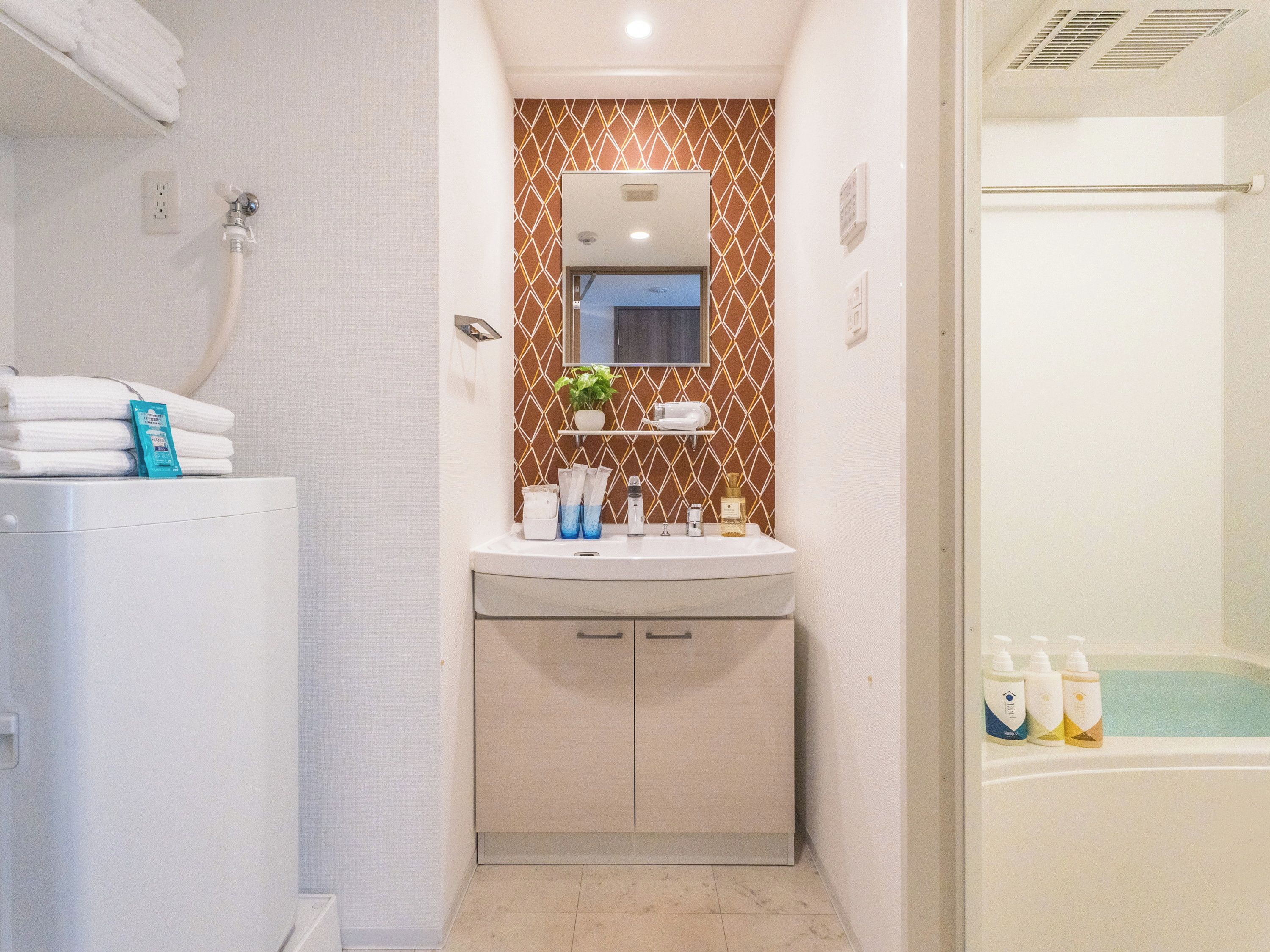 A bathroom with a white sink, a mirror, a towel rack, and a shower area.