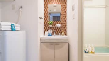 A bathroom with a white sink, a mirror, a towel rack, and a shower area.