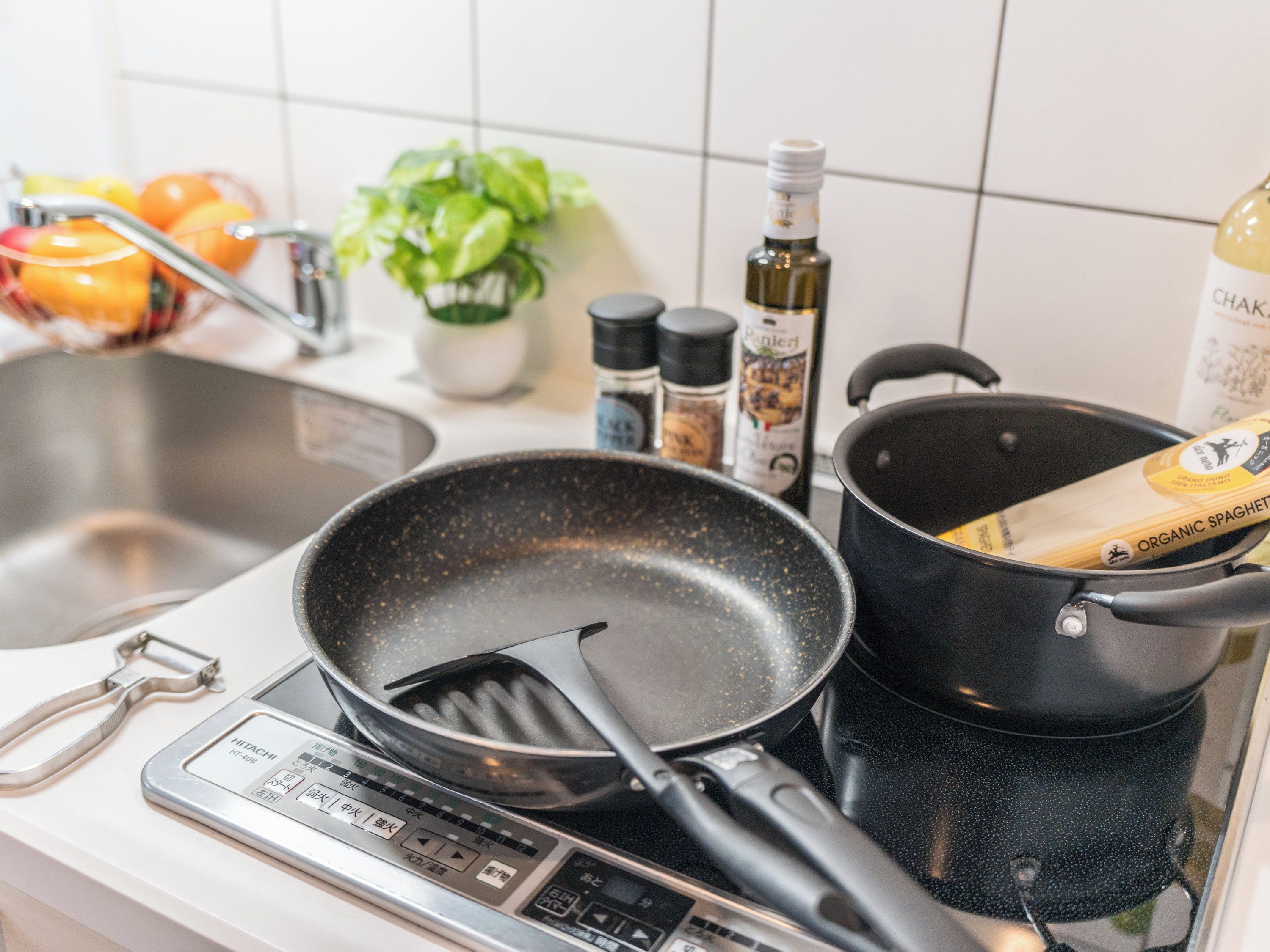 A kitchen with a stove, a frying pan, a pot, and various kitchen utensils.